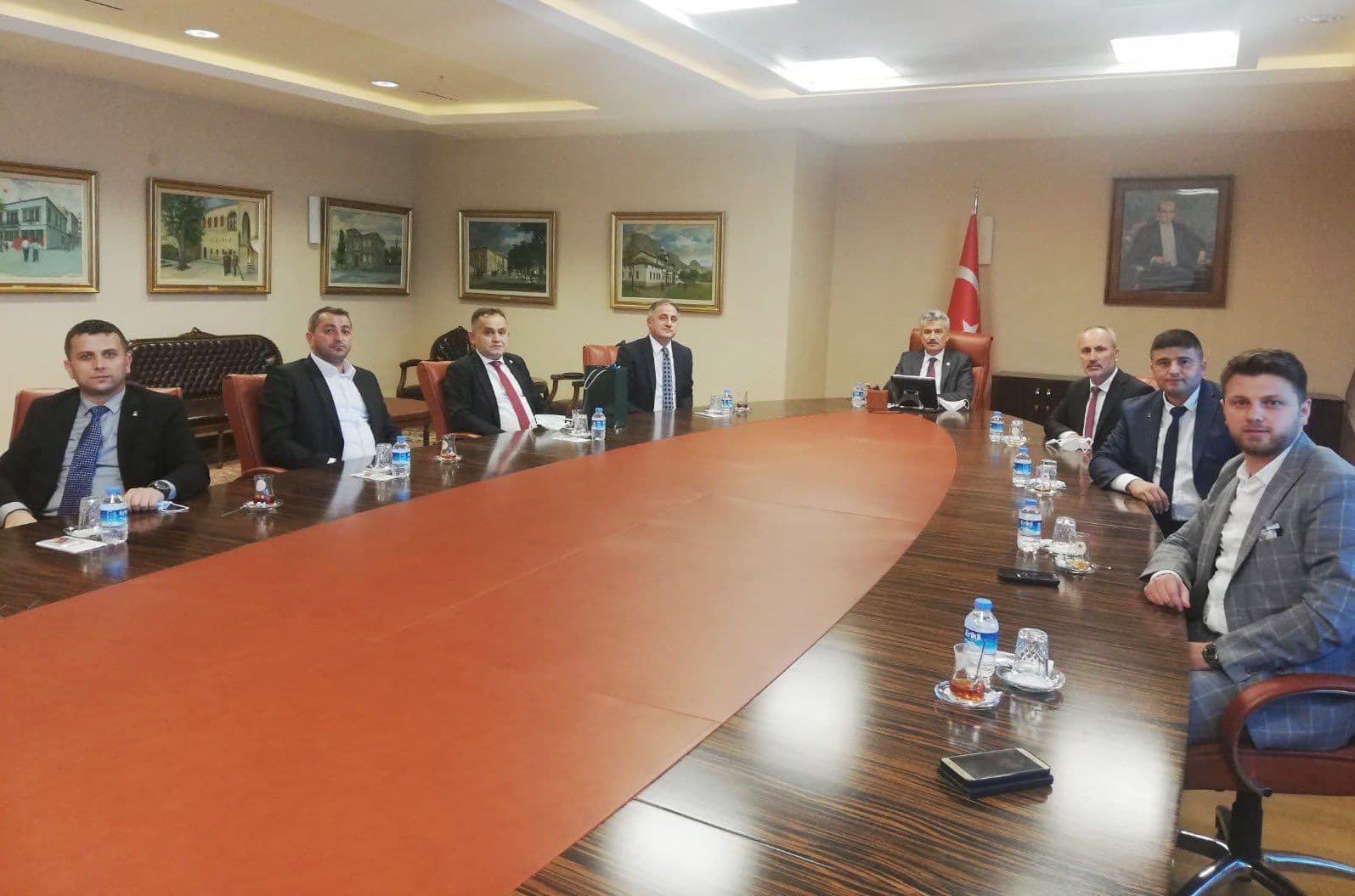 Uzun toplantı masası etrafında sekiz kişilik resmi görüşme