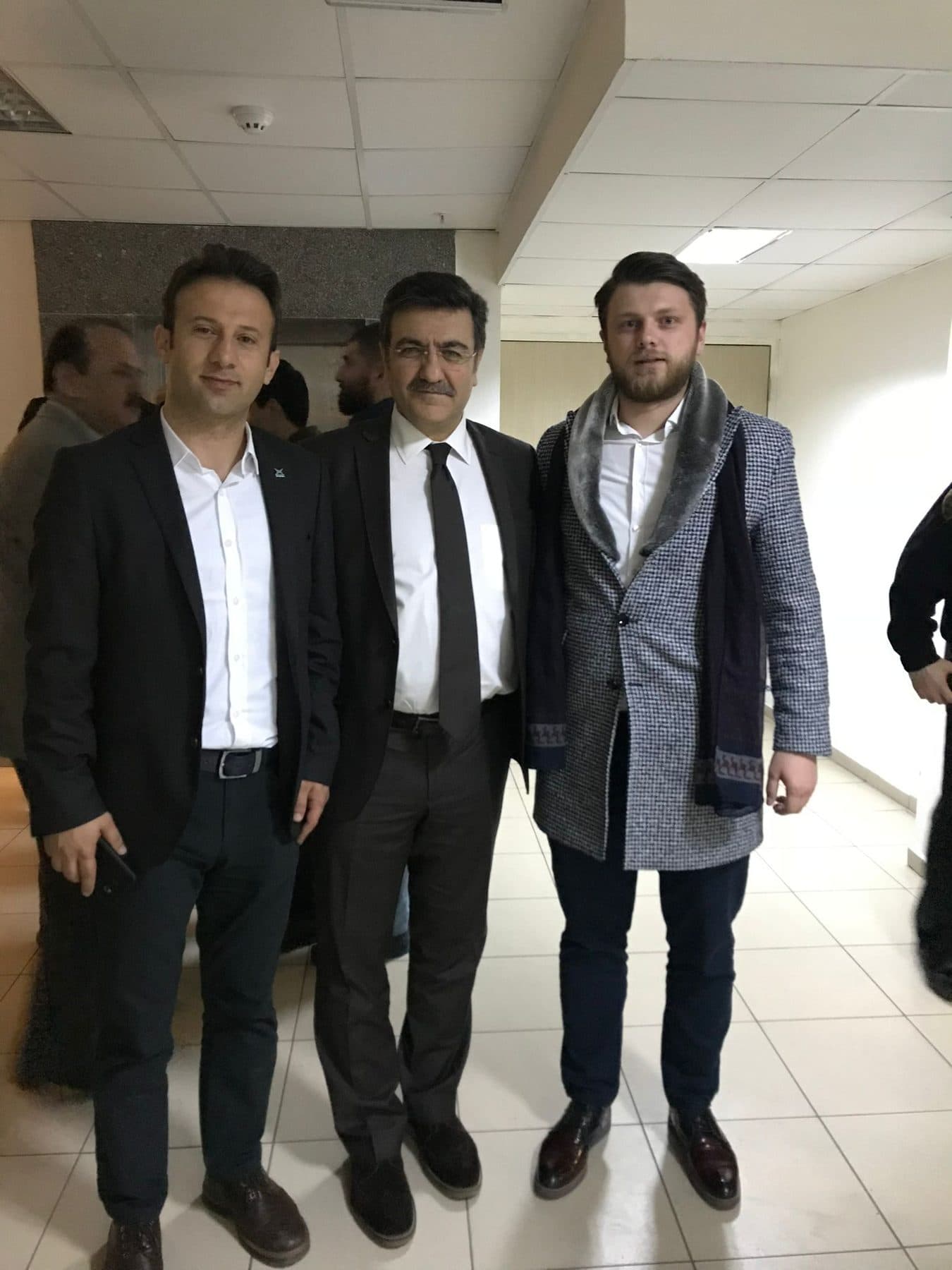 Ömer Yazıcıoğlu, bir iç mekânda iki kişiyle birlikte