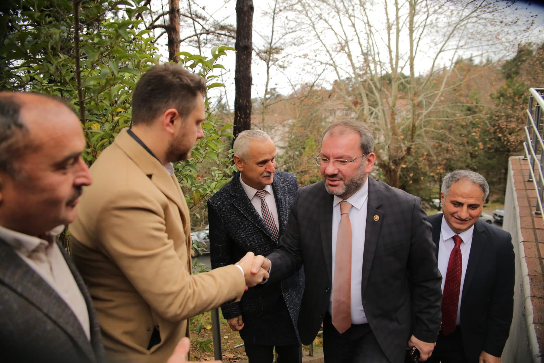 Ömer Yazıcıoğlu, açık havada karşıladığı konuklardan biriyle tokalaşırken