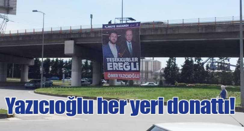 Şehir girişindeki köprüye asılan tebrik afişi ve çevresindeki yol manzarası